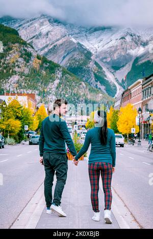 Ein Paar besucht die Stadt Banff Alberta Kanada, ein Paar Männer und Frauen, die auf der Straße von Banff mit riesigen felsigen Bergen im Hintergrund in Kanada spazieren gehen. Stockfoto