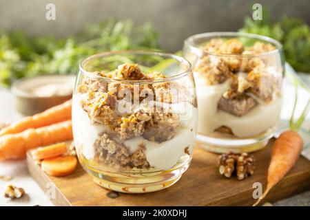 Gesundes Dessert. Veganes glutenfreies Gebäck. Karottenkuchen mit Walnüssen und Zimt in einem Glas auf hellem Hintergrund. Stockfoto