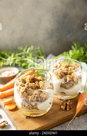Gesundes Dessert. Veganes glutenfreies Gebäck. Karottenkuchen mit Walnüssen und Zimt in einem Glas auf hellem Hintergrund. Speicherplatz kopieren. Stockfoto