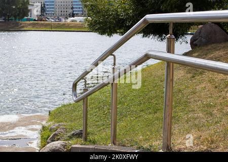 Metallgeländer an der Treppe in der Nähe des Teiches aus der Nähe Stockfoto