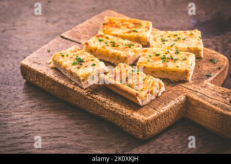 Zwiebelkuchen – hausgemachter, herzhafter deutscher Zwiebelkuchen oder Kuchen mit gedämpften Zwiebeln und Speck auf einem Holzbrett Stockfoto