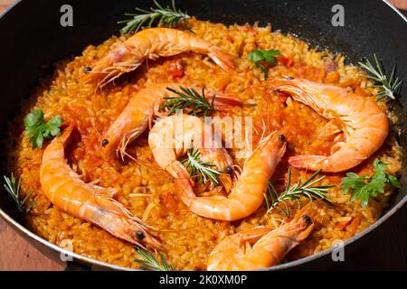 Paella ist ein traditionelles spanisches Essen. Paella mit Meeresfrüchten in einer Pfanne mit Garnelen. Kochen Paella auf der Straße, Nahaufnahme. mediterrane Meeresfrüchte-Gericht Stockfoto