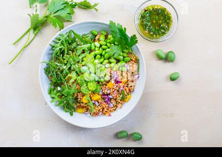 Gesunder Couscous-Salat mit Edamamabohnen, Rucola und Cucamelon (mexikanische Miniatur-Wassermelone), mit Zitronen- und Kräuterdressing Stockfoto