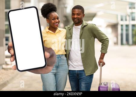 Afroamerikanisches Touristen-Paar Zeigt Riesigen Handy-Bildschirm Am Flughafen Stockfoto