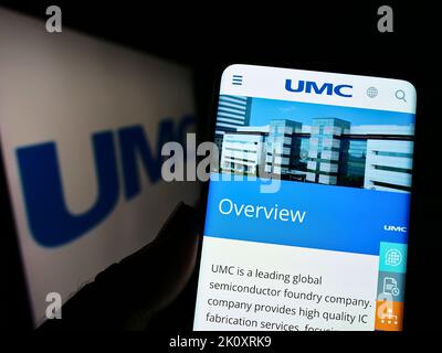Person, die Mobiltelefon mit Website der Firma United Microelectronics Corporation (UMC) auf dem Bildschirm mit Logo hält. Konzentrieren Sie sich auf die Mitte des Telefondisplays. Stockfoto