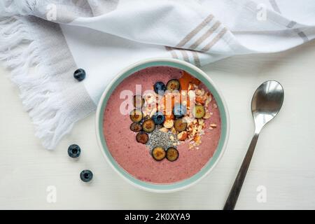 Gesunde, geglättet Schale mit Chiasamen, Heidelbeeren, Nüssen und Erdnussbutter auf weißer Serviette. Veganes Frühstück, Blick von oben, flach liegend. Stockfoto