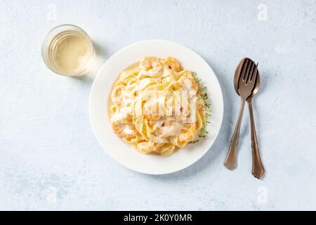 Italienische Pasta mit Meeresfrüchten. Pappardelle mit Garnelen und Sahnesauce, darüber liegend flach mit Wein beschossen Stockfoto