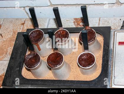 Traditioneller türkischer Kaffee mit Schaum in Cezve, zubereitet auf heißem Sand in authentischem türkischen Kupfer oder einer Kaffeemaschine. Stockfoto