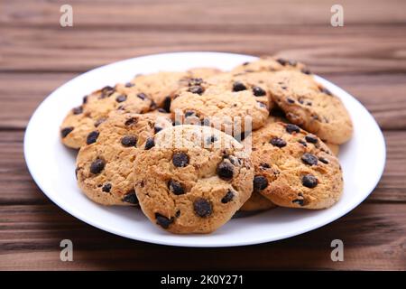 Schokoladenkekse auf dem Teller auf dem braunen Holztisch Stockfoto