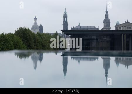 Dresden, Deutschland. 14. September 2022. Die Kulisse der Dresdner Altstadt mit der Frauenkirche (l-r), dem Ständehaus, der katholischen Hofkirche, dem Schlosssturm und der Semperoper spiegelt sich in einer mit Regenwasser bedeckten Scheibe wider. Quelle: Sebastian Kahnert/dpa/Alamy Live News Stockfoto
