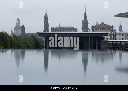 Dresden, Deutschland. 14. September 2022. Die Kulisse der Dresdner Altstadt mit der Frauenkirche (l-r), dem Ständehaus, der katholischen Hofkirche, dem Schlosssturm und der Semperoper spiegelt sich in einer mit Regenwasser bedeckten Scheibe wider. Quelle: Sebastian Kahnert/dpa/Alamy Live News Stockfoto