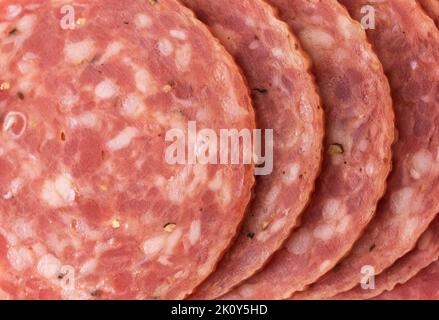 Nahansicht mehrerer Scheiben trockener Salami, die mit natürlichem Licht beleuchtet sind. Stockfoto