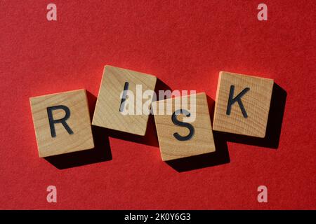 Risiko, Wort in Holzbuchstaben isoliert auf hellrotem Hintergrund Stockfoto