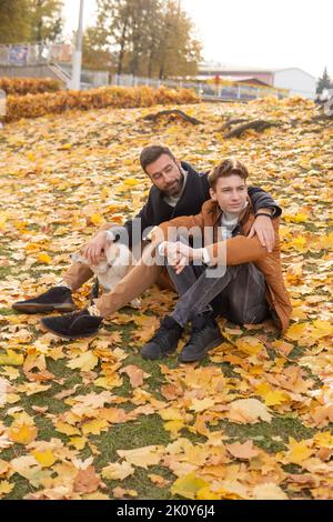 Vater und Sohn mit einem Haustier auf einem Spaziergang im Herbstpark. Stockfoto