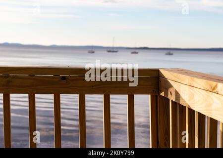 Handlauf im Vordergrund mit Penobscot Bay und verankerten Booten im Hintergrund im frühen Morgenlicht. Stockfoto