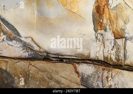 Felsenhintergrund mit Rissen und bunten Streifen im frühen Morgenlicht. Stockfoto
