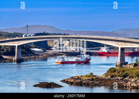 KYLE VON LOCHALSH SCHOTTLAND IM SPÄTSOMMER EIN ORANGEFARBENES MOWI-SCHIFF, DAS UNTER DER SKYE-BRÜCKE VORBEIFÄHRT Stockfoto