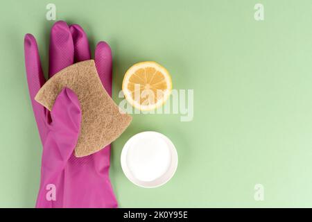 Natürliche Haushaltsreiniger - Öko-Schwamm mit Backpulver oder Zitronensäure und Zitrone auf grünem Hintergrund mit Kopierfläche. Hausgemachte improvisierte Reinigung Stockfoto