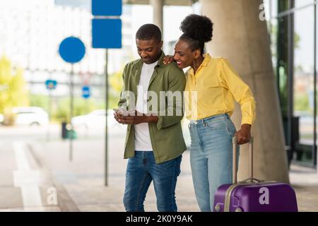 Schwarze Touristen Ehepartner Mit Mobiltelefon Stehen Mit Koffer In Der Nähe Des Flughafens Stockfoto