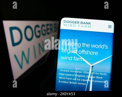 Person hält Handy mit Website des Offshore-Energieerzeugers Dogger Bank Wind Farm auf dem Bildschirm mit Logo. Konzentrieren Sie sich auf die Mitte des Telefondisplays. Stockfoto