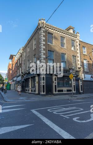 Eine Eckstraße mit Backsteingebäuden in der Stadt Dublin und Straßenschild im Vordergrund. Stockfoto