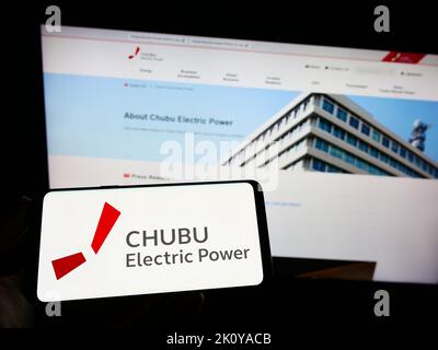 Person, die das Smartphone mit dem Logo des japanischen Unternehmens Chubu Electric Power Co. Inc. Auf dem Bildschirm vor der Website hält. Konzentrieren Sie sich auf die Telefonanzeige. Stockfoto