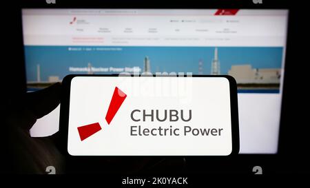 Person, die das Mobiltelefon mit dem Logo des japanischen Unternehmens Chubu Electric Power Co. Inc. Auf dem Bildschirm vor der Webseite hält. Konzentrieren Sie sich auf die Telefonanzeige. Stockfoto