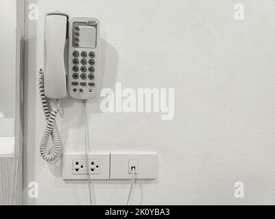 Telefon an weißer Wand. Telefon für Zimmerservice, Kommunikationsthemen im Hotelzimmer Stockfoto