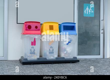 Drei bunte Papierkorb vor den öffentlichen Toiletten. Behälter mit Recycling-Symbol Stockfoto