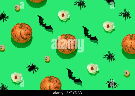 Halloween-Muster mit orangefarbenen Kürbissen, schwarzen Fledermäusen und Spinnen, Augäpfel und weißen Blüten auf grünem Hintergrund. Stockfoto