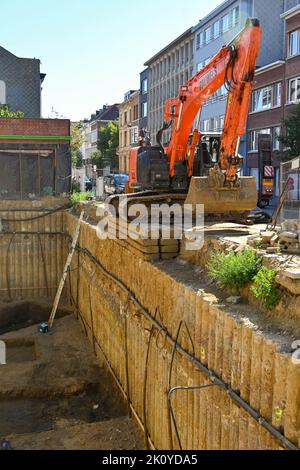 Antwerpen, Belgien - August 2022: Mechanischer Bagger, der am Rand eines großen Lochs für die Fundamente eines neuen Gebäudes geparkt ist Stockfoto