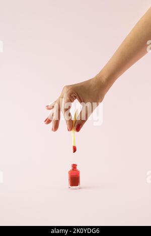 Handgedippte frittierte Kartoffel in rotem Nagellack auf rosa Hintergrund. Minimalkonzept. Stockfoto