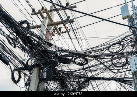 Verworrene elektrische Drähte auf dem städtischen Strommast. Unorganisiert und chaotisch zu Organisationsmanagement-Konzept. Nahaufnahme verwickelte elektrische Leitungen Stockfoto