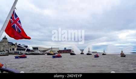 Flussschlepper führen Fleur De Lis vor, als sich Schiffe auf dem River Mersey in Liverpool vor den Three Graces (Liver Building, Cunard Building und Port of Liverpool Building) für eine maritime Hommage an Königin Elizabeth II. Versammeln. Die vor ihrer Beerdigung am Montag in der Westminster Hall in London im Staat liegen wird. Bilddatum: Mittwoch, 14. September 2022. Stockfoto