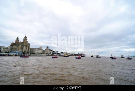 Flussschlepper führen Fleur De Lis vor, als sich Schiffe auf dem River Mersey in Liverpool vor den Three Graces (Liver Building, Cunard Building und Port of Liverpool Building) für eine maritime Hommage an Königin Elizabeth II. Versammeln. Die vor ihrer Beerdigung am Montag in der Westminster Hall in London im Staat liegen wird. Bilddatum: Mittwoch, 14. September 2022. Stockfoto