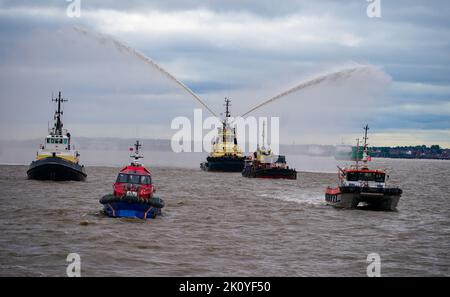 Flussschlepper führen Fleur De Lis vor, als sich Schiffe auf dem River Mersey in Liverpool vor den Three Graces (Liver Building, Cunard Building und Port of Liverpool Building) für eine maritime Hommage an Königin Elizabeth II. Versammeln. Die vor ihrer Beerdigung am Montag in der Westminster Hall in London im Staat liegen wird. Bilddatum: Mittwoch, 14. September 2022. Stockfoto