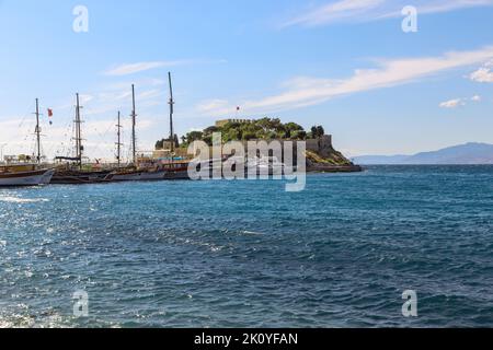 KUSADASI, TÜRKEI - 2. JUNI 2021: Dies ist die osmanische Festung von Guverjinada (15.. Jahrhundert) und der Pier für Vergnügungsschiffe. Stockfoto