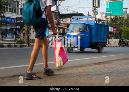 April 13. 2022, Dehradun City Uttarakhand Indien. Traditionelle blaue Dreirad-Auto-Rikscha, die Waren auf den Straßen mit einem Passanten vorne transportiert. Stockfoto