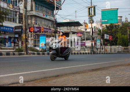 April 13. 2022, Dehradun City Uttarakhand Indien. Eine junge Dame, die auf dem Roller zur Arbeit reitet. Stockfoto