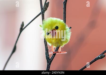 Ein gelbes Osterhuhnschmuck, versteckt in einem Busch Stockfoto