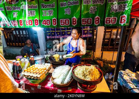 CHIANG MAI, THAILAND - 3.11.2019: Frauen bereiten auf dem Nachtmarkt in Chiang Mai Street Food zu. Berühmtes thailändisches Essen namens Pad Thai, bestellt von t Stockfoto