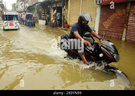 Dhaka. 14. September 2022. Am 14. September 2022 fährt ein Mann auf einer wasserbefahrbaren Straße in Dhaka, Bangladesch, ein Motorrad. Moderate bis schwere Regenfälle haben am Mittwoch Teile der bangladeschischen Hauptstadt Dhaka heimgesucht, tief liegende Gebiete invutiert und den Straßenverkehr gestört. Quelle: Xinhua/Alamy Live News Stockfoto