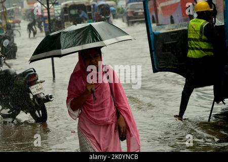 Dhaka. 14. September 2022. Eine Frau mit einem Regenschirm wat am 14. September 2022 durch eine wasserbefahrbare Straße in Dhaka, Bangladesch. Moderate bis schwere Regenfälle haben am Mittwoch Teile der bangladeschischen Hauptstadt Dhaka heimgesucht, tief liegende Gebiete invutiert und den Straßenverkehr gestört. Quelle: Xinhua/Alamy Live News Stockfoto