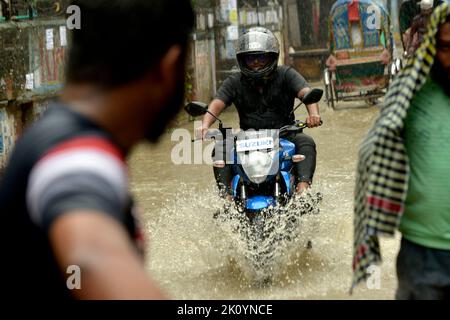 Dhaka. 14. September 2022. Am 14. September 2022 fährt ein Mann auf einer wasserbefahrbaren Straße in Dhaka, Bangladesch, ein Motorrad. Moderate bis schwere Regenfälle haben am Mittwoch Teile der bangladeschischen Hauptstadt Dhaka heimgesucht, tief liegende Gebiete invutiert und den Straßenverkehr gestört. Quelle: Xinhua/Alamy Live News Stockfoto