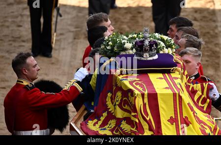 Die Trägerpartei der Queen's Company, 1. Bataillon Grenadier Guards, trägt den Sarg von Königin Elizabeth II., der im Royal Standard mit der oben platzierten Kaiserlichen Staatskrone drapiert ist, in die Westminster Hall, London, wo er vor ihrer Beerdigung am Montag im Zustand liegen wird. Bilddatum: Mittwoch, 14. September 2022. Stockfoto