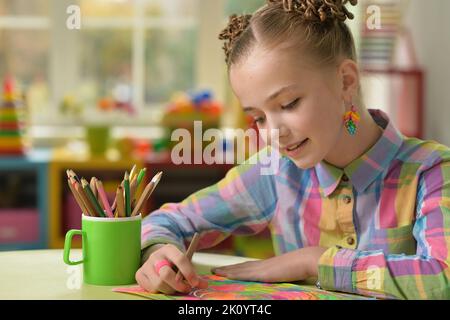Schönes kleines Mädchen zeichnet mit einem Bleistift auf ein Blatt Papier Stockfoto