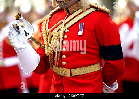 Nahaufnahme des schwarzen Armbands auf der Militärprozession, während der Sarg von Königin Elisabeth II., drapiert im Royal Standard mit der kaiserlichen Staatskrone auf der Oberseite, auf einem Pferdegewehrwagen der Königstruppe Royal Horse Artillery getragen wird, Während der feierlichen Prozession vom Buckingham Palace zur Westminster Hall, London, wo sie vor ihrer Beerdigung am Montag in einem Zustand liegen wird. Bilddatum: Mittwoch, 14. September 2022. Stockfoto