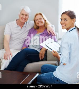 Termin muss nicht stressig sein. Ein glückliches Seniorenpaar mit einer jungen Krankenschwester, während sie ein digitales Tablet hält. Stockfoto