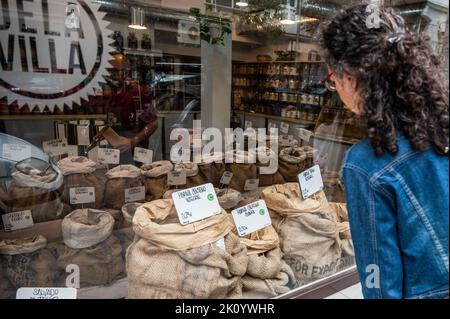 Madrid, Spanien. 14. September 2022. Eine Frau schaut auf ein Fenster eines Bioladen, in dem verschiedene Mehlsorten, Getreide und Hülsenfrüchte zu sehen sind. Dürre, schlechtes Wetter und hohe Temperaturen drohen zusammen mit der Kriegslage in der Ukraine einen Anstieg der Preise für landwirtschaftliche Rohstoffe. Die Hauptgetreide und Hülsenfrüchte weisen nach Ansicht mehrerer Bauernverbände auf einen Anstieg von mehr als 10 % hin. Quelle: Marcos del Mazo/Alamy Live News Stockfoto