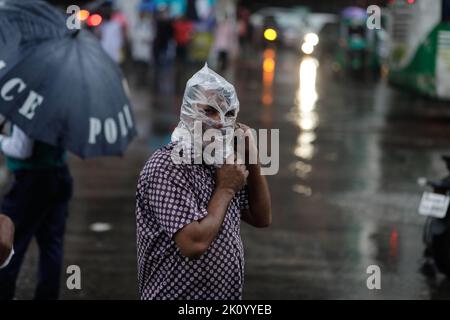 Dhaka, Bangladesch. 14. September 2022. Ein Mann posiert wegen eines Fotos, der seinen Kopf wegen Regen mit einer Plastiktüte bedeckt, während er am Mittwoch, 14. September 2022, nach Hause nach dem Büro in Dhaka, Bangladesch, geht. Die Hauptstadt Dhaka verzeichnete in den letzten 24 Stunden unter dem Einfluss des Niederdrucks in der Bucht von Bengalen 53 mm Regen. (Bild: © Md. Rakibul Hasan/ZUMA Press Wire) Bild: ZUMA Press, Inc./Alamy Live News Stockfoto